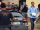 Joseph Rabelo,de óculos escuros, que encobre com um papel as algemas, é apontado pela polícia como líder da organização criminosa.