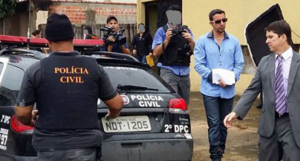 Joseph Rabelo,de óculos escuros, que encobre com um papel as algemas, é apontado pela polícia como líder da organização criminosa.