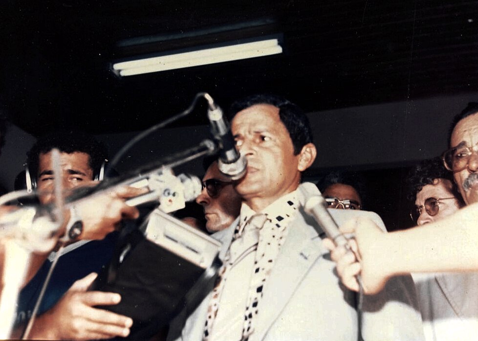Manoel Félix durante coletiva de imprensa. à esquerda com fone de ouvido o radialista Aldenor Soares; atrás o governador Ângelo Angelim, do outro lado, atrás, o radialista Valdemar Camata 